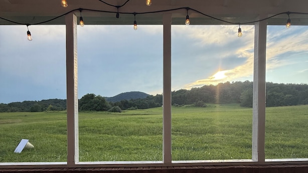 A room with a large glass table, multiple windows, and string lights. - Charming Farmhouse near Inn at Little Washington (Washington)