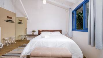 Un dormitorio con una cama grande, cabecera de madera, una mesita pequeña y un banco.
