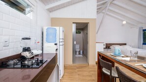 Uma cozinha moderna com fogão a gás, dispensador de água e geladeira. Há uma área de jantar com mesa e cadeiras.