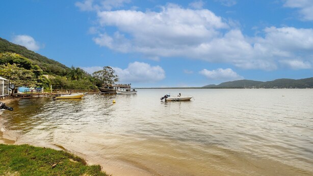 Um lago calmo com barcos, um cais e margens gramadas.
