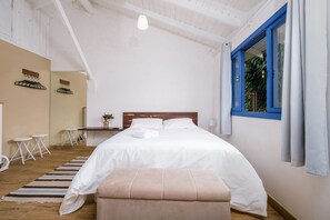 A bedroom with a large bed, a wooden headboard, a small table, and a bench. - Charming Studio Edge of Lagoa da Conceicao Jhg1733 (Florianópolis)