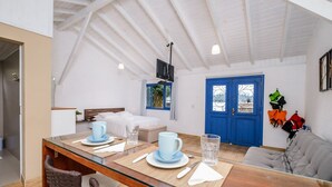 Um quarto aconchegante com área de refeições, uma cama e uma porta azul.