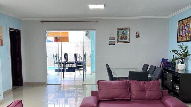 A spacious living area with a large sofa and a dining table, a sliding glass door leading to an outdoor patio, and a small decorative shelf with a plant. - Casa COP30 14 leitos, Condominio Segurança armada 24h (Tapanã Belém)