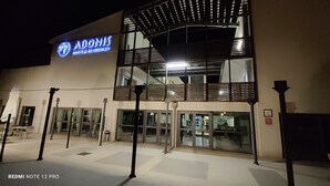 Un hôtel appelé « Adonis », doté d’une architecture moderne, se distingue par une enseigne bien visible et une entrée en verre.