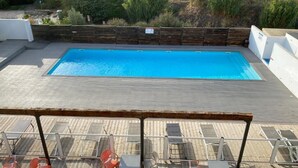 Une piscine rectangulaire dotée d’une terrasse en bois et de chaises longues.