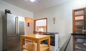 Una cocina compacta con refrigerador, estufa y una mesa de comedor de madera.