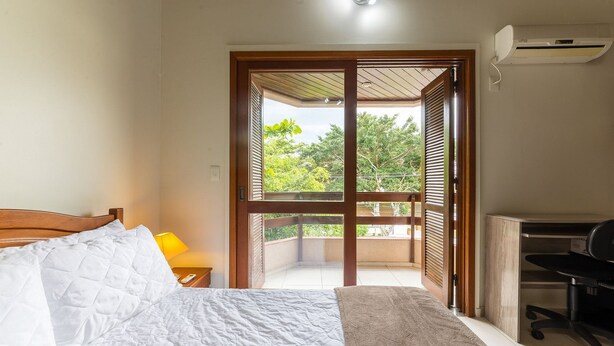 A bedroom with a bed, a desk, and a view of a balcony. - 2-bedr Ap W/bbq, 400m From the Beach Jurere Jba202 (Florianópolis)