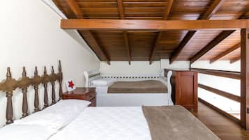Un dormitorio con dos camas, vigas de madera en el techo, una mesita de noche y una ventana con vistas.