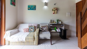A cozy living room with a sofa, a chair, and a small table. There are wall decorations and a light fixture. - 2-bedr Ap W/bbq, 400m From the Beach Jurere Jba202 (Florianópolis)