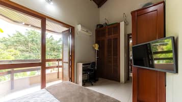 Un dormitorio con una cama, un escritorio, una silla, aire acondicionado y televisor.