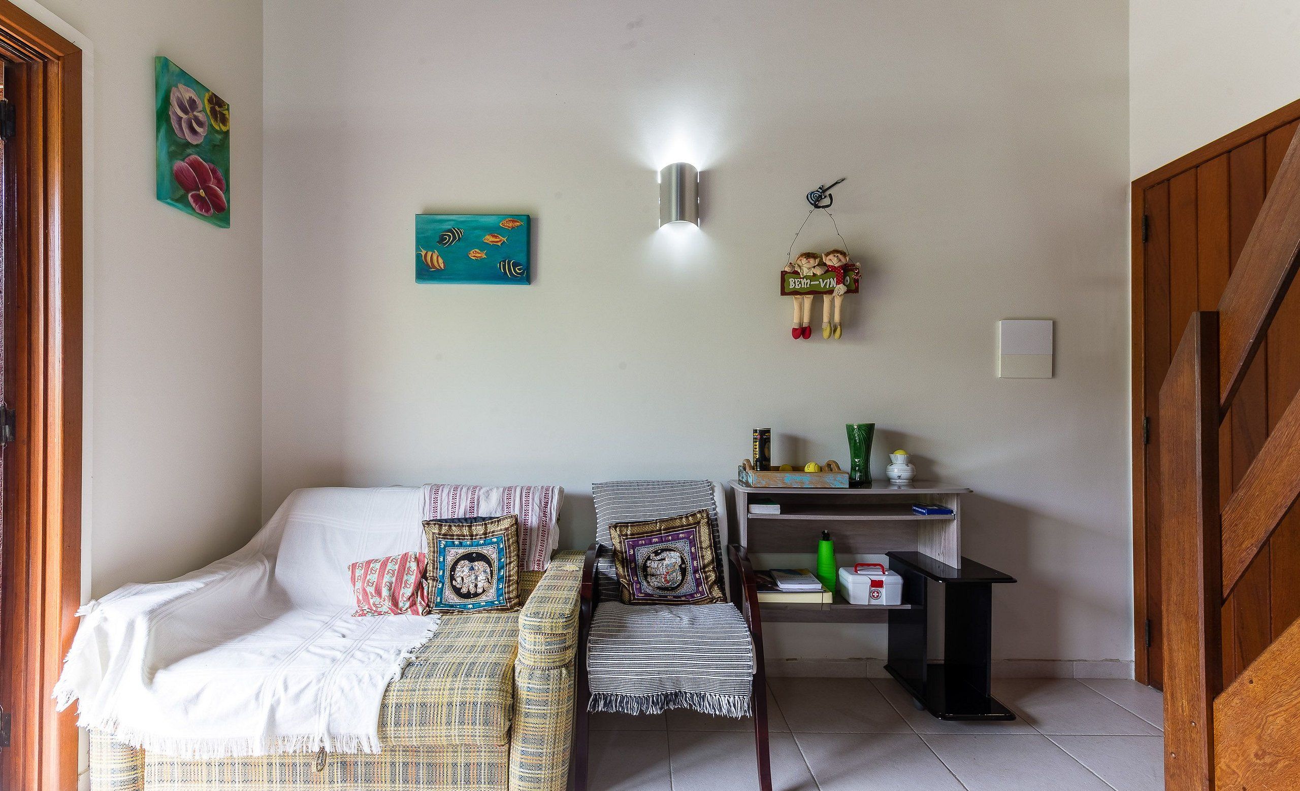 A cozy living room with a sofa, a chair, and a small table. There are wall decorations and a light fixture.