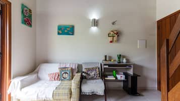 A cozy living room with a sofa, a chair, and a small table. There are wall decorations and a light fixture.