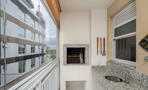 Un balcón con vista a un edificio moderno, una pequeña chimenea y un lavamanos de granito.