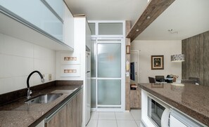 Une cuisine moderne dotée d’un plan de travail en granit, d’un évier en acier inoxydable et d’une porte-fenêtre coulissante donnant sur un coin repas.
