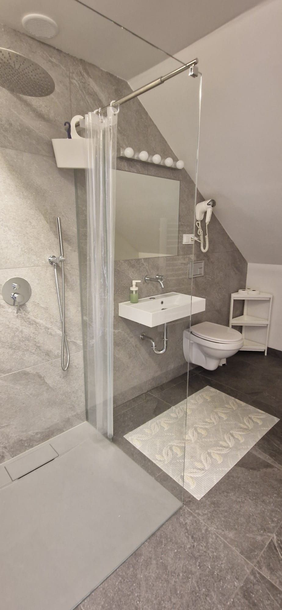 Een moderne badkamer met douche, toilet en wastafel.