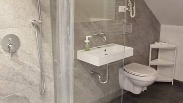 Een moderne badkamer met douche, toilet en wastafel.