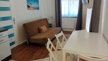 En hyggelig stue med en brun sofa, et hvidt spisebord og et fjernsyn ophængt på væggen.