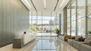 A modern reception area with a marble floor, a reception desk, and a seating area with sofas. - Apartment 9th Floor Luxury Suites District (Barranquilla)