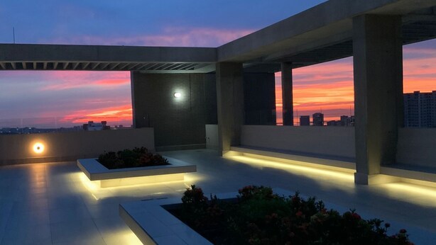A rooftop terrace with a sunset view, concrete structures, and illuminated planters. - Apartment 9th Floor Luxury Suites District (Barranquilla)