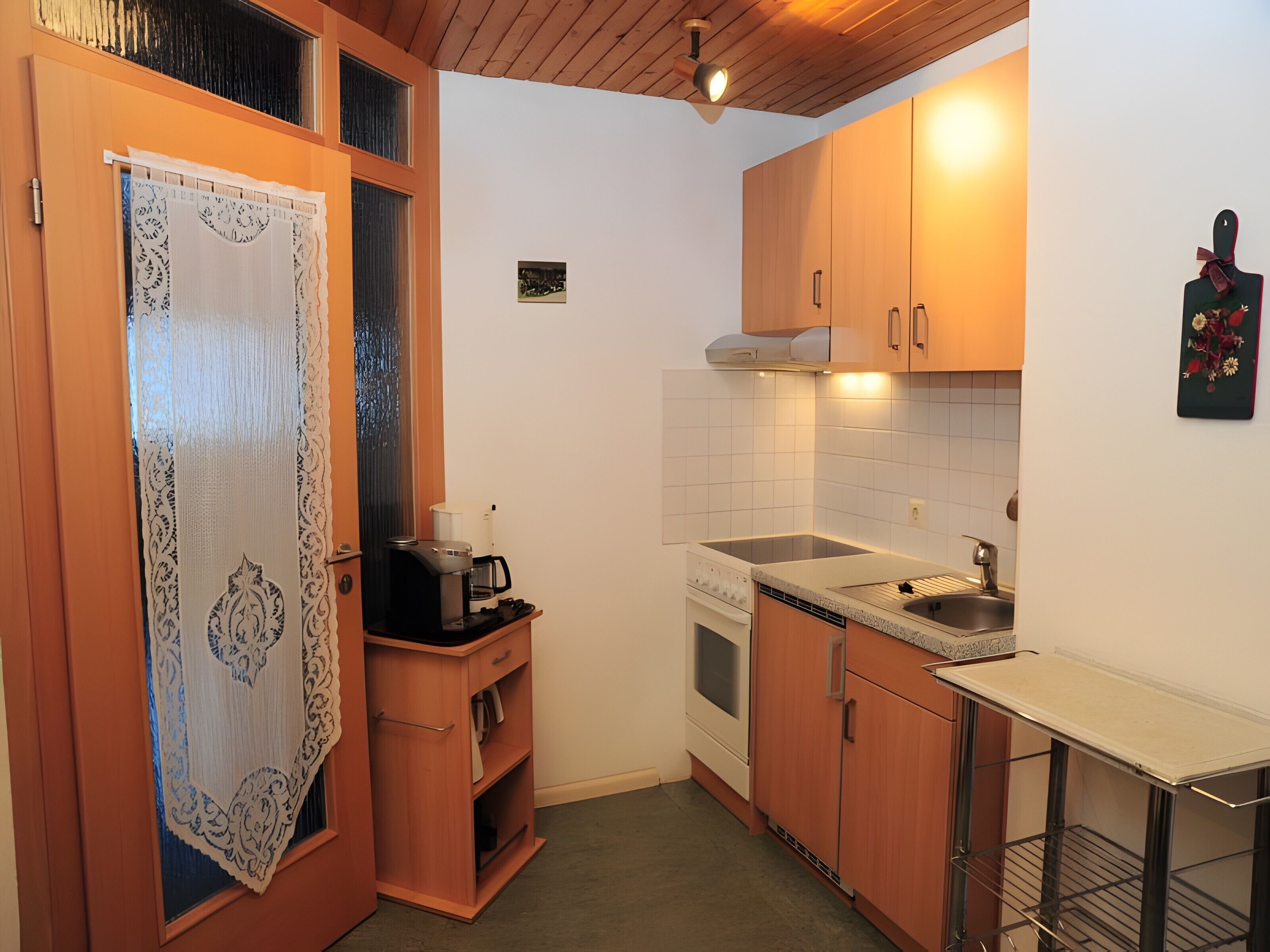 Une cuisine compacte avec des meubles en bois, un four encastré, un évier et un petit plan de travail.