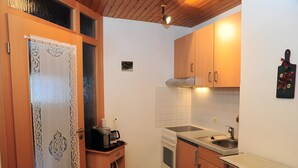 A compact kitchen with wooden cabinets, a built-in oven, a sink, and a small countertop.