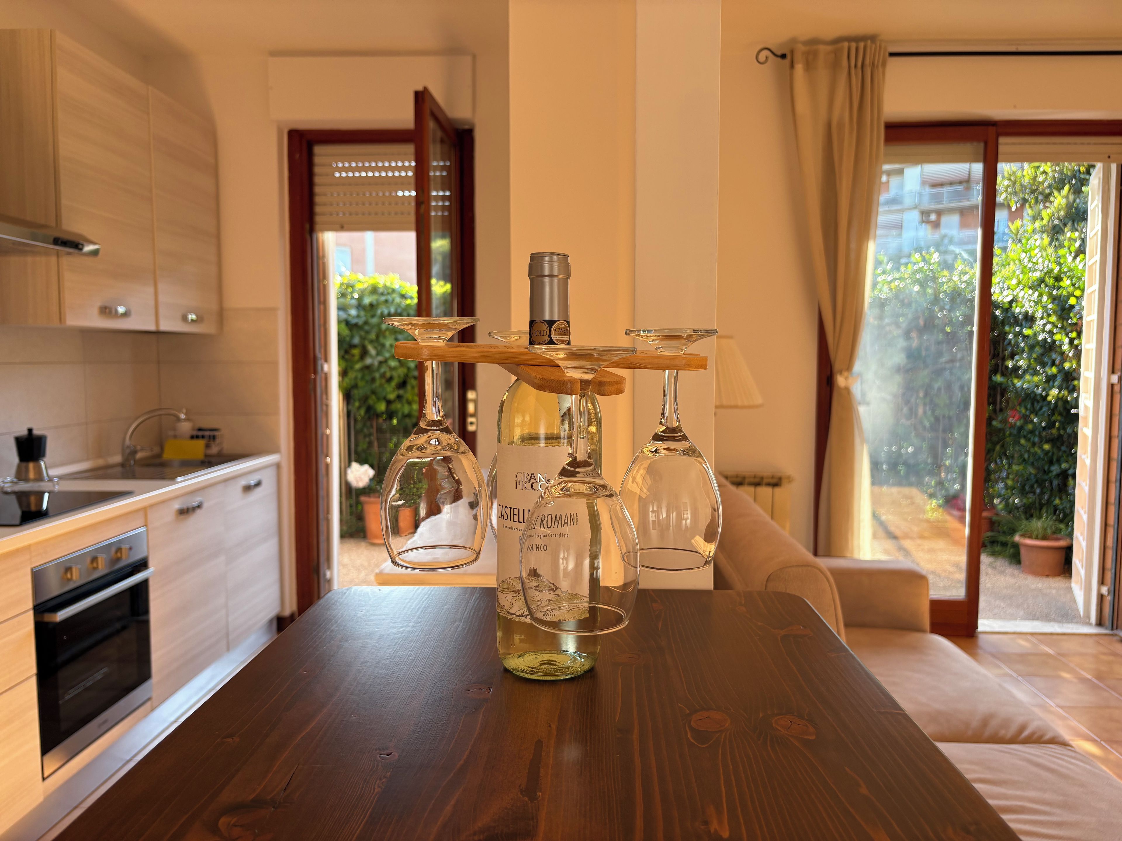Una cucina moderna con un tavolo in legno su cui sono esposti bicchieri da vino e una bottiglia.