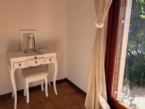 A white dresser with a mirror and two drawers, positioned next to a window with a curtain. - Casa dell'angelo labaro (Roma)