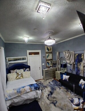 A bedroom with a bed, a dresser, a mirror, and a chandelier.