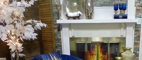 A living room with a blue sofa, a white fluffy rug, a fireplace, and decorative items on a mantel.
