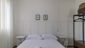 Ett sovrum med en säng, två sängbord, en garderob och två inramade tavlor på väggen.