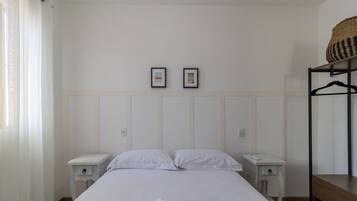 A bedroom with a bed, two bedside tables, a wardrobe, and two framed pictures on the wall.