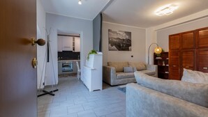 Una sala de estar moderna con un sofá, un comedor con una mesa y sillas, y una cocina al fondo.