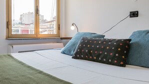 Un dormitorio con cama, ventana, enchufe y radiador.