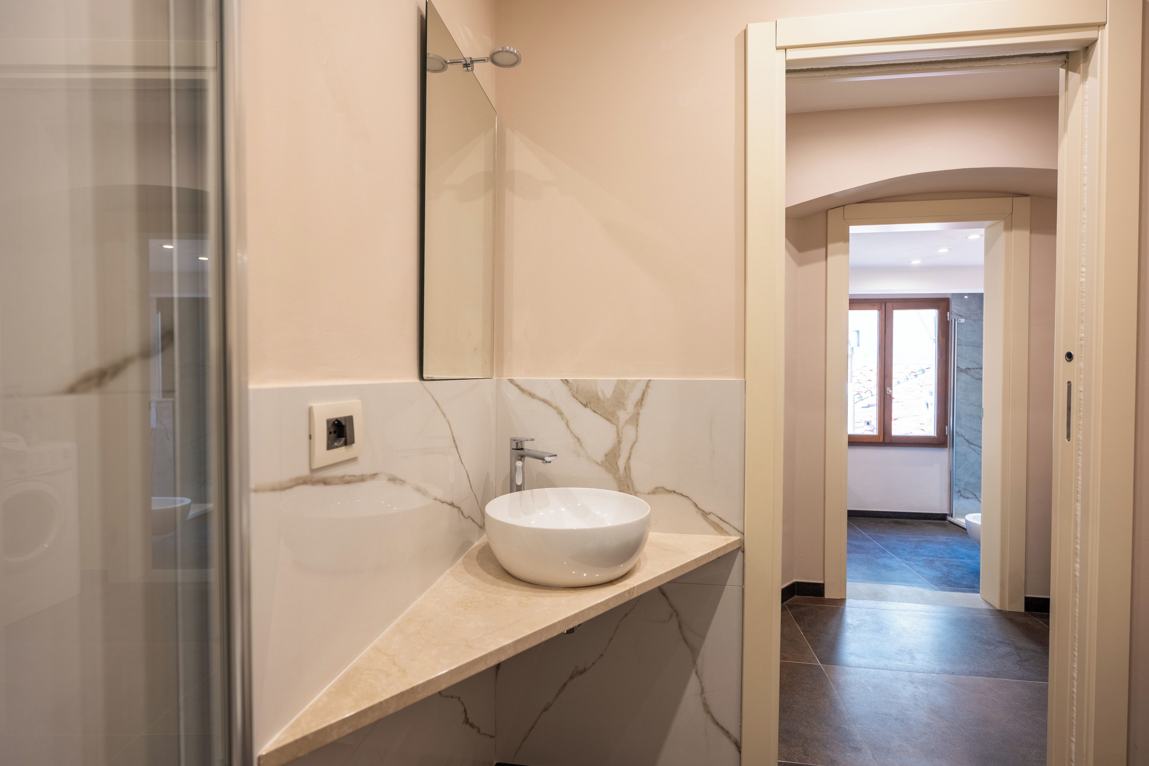 Une salle de bain avec un lavabo en marbre, un miroir et une douche.