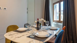 A dining area with a marble table, white plates, wine bottle, and glasses. - Florence Dome Rooms (Florence)