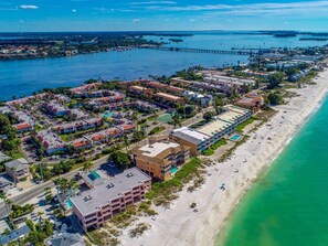 An aerial view of a coastal resort area with multiple buildings, a beach, and a pier. - Island Oasis Retreat - 1 Minute Walk to the Beach (Bradenton Beach)