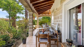 A covered patio with a table and chairs, surrounded by potted plants and a stone wall. - Bed and Breakfast 'Gautama' with Mountain View, Shared Terrace and Shared Garden (SARROLA CARCOPINO)