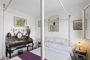 Une chambre à coucher avec un lit, une commode, un miroir et une table de chevet avec une lampe.