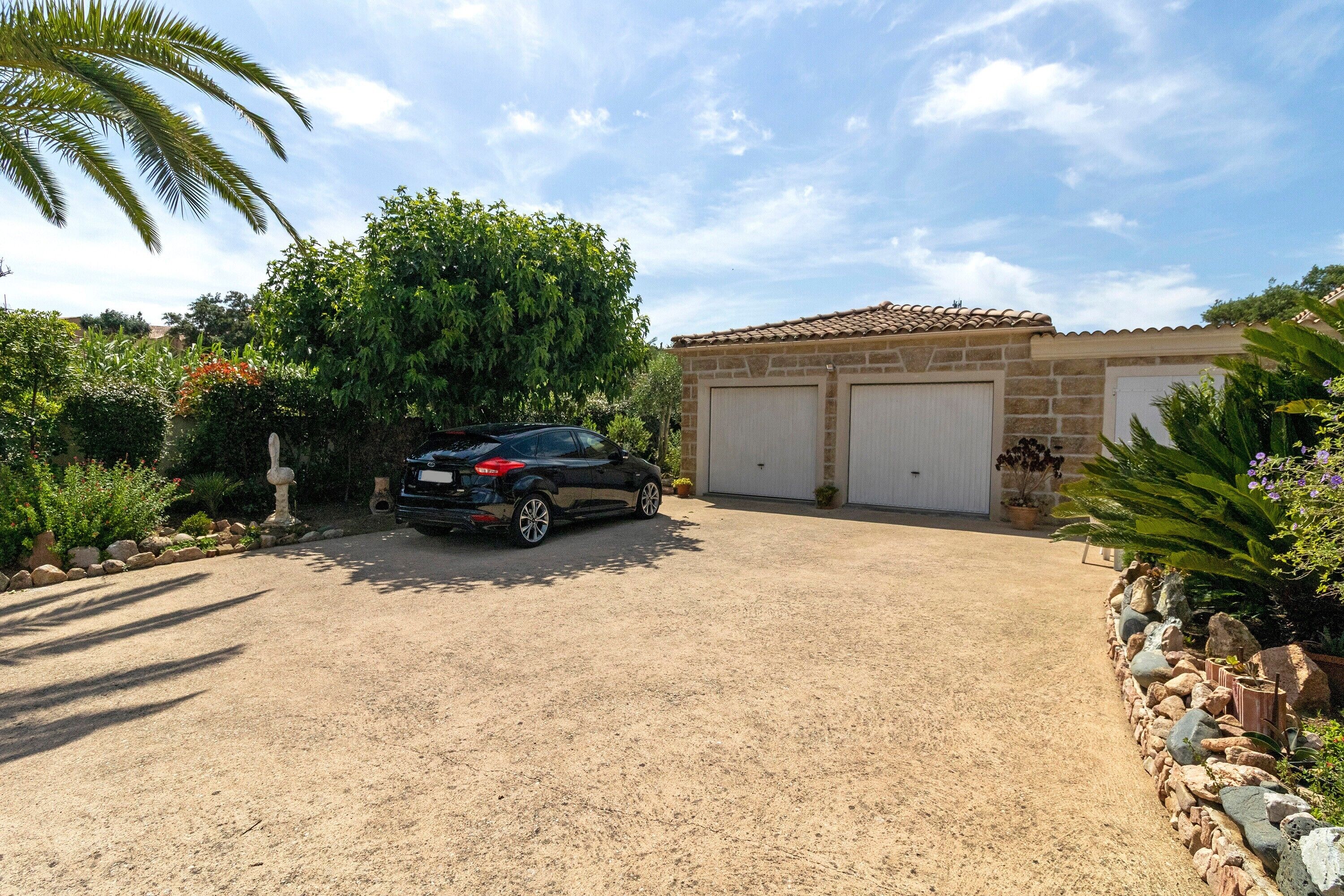 Une maison avec un garage, une allée et de la verdure tout autour.