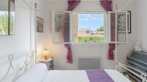 A bedroom with a bed, a bedside table with a lamp, a dresser, and a window with curtains. - Bed and Breakfast 'Gautama' with Mountain View, Shared Terrace and Shared Garden (SARROLA CARCOPINO)