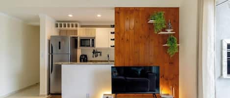 Una cocina moderna con microondas integrado, refrigerador y una pequeña isla con televisor de pantalla plana.