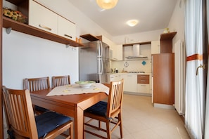 Una cocina funcional con comedor, muebles de madera y electrodomésticos integrados.