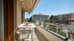 A balcony with a table and chairs, a view of neighboring buildings, and a clear sky. - Casa Andrea with Balcony, Wi-Fi, and Air Conditioning (Venezia)