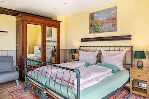 A bedroom with a metal bed frame, a wooden wardrobe, a bedside table with a lamp, and a painting on the wall. - Apartment "Green" with Private Terrace, Shared Garden, and Wi-Fi (Bad Krozingen)