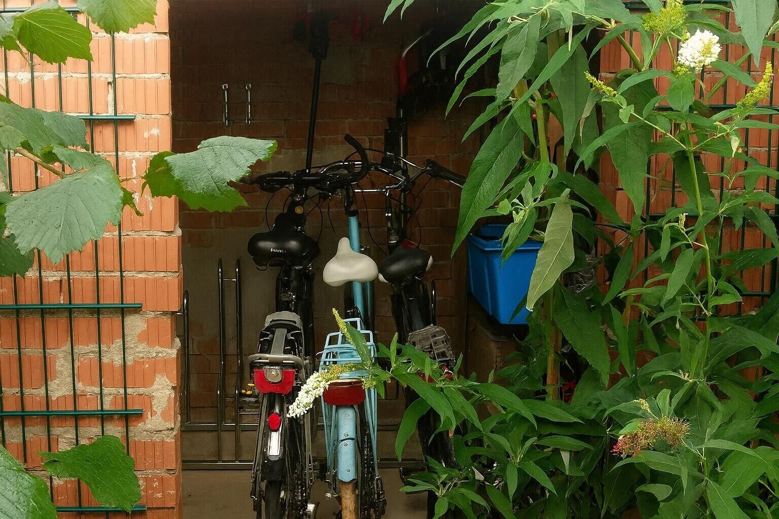 A brick wall with a bicycle rack holding two bicycles.