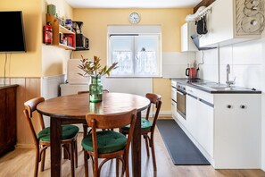 Una cucina con tavolo da pranzo, sedie, orologio e finestra.