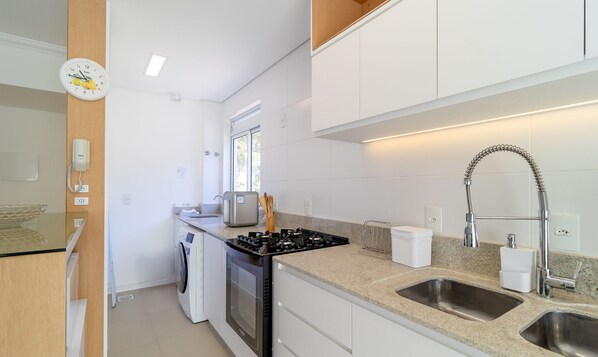 A compact kitchen with a gas stove, two sinks, a built-in oven, and a microwave. - Beautiful apt With Barbecue in Floripa Ibe104 (Florianópolis)