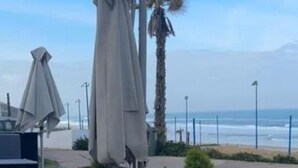 Outdoor seating with tables and umbrellas, a wooden planter, and a view of the beach. - Prestigia Luxury apartment near the beach "Plage Des Nations" Sale/Rabat/Airport (Rabat-Salé-Kénitra)