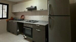 A modern kitchen with a stainless steel refrigerator, a built-in oven, and a gas stove. - Prestigia Luxury apartment near the beach "Plage Des Nations" Sale/Rabat/Airport (Rabat-Salé-Kénitra)