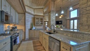 Une cuisine spacieuse dotée de plans de travail en granit, d’armoires en bois et d’un grand îlot central.